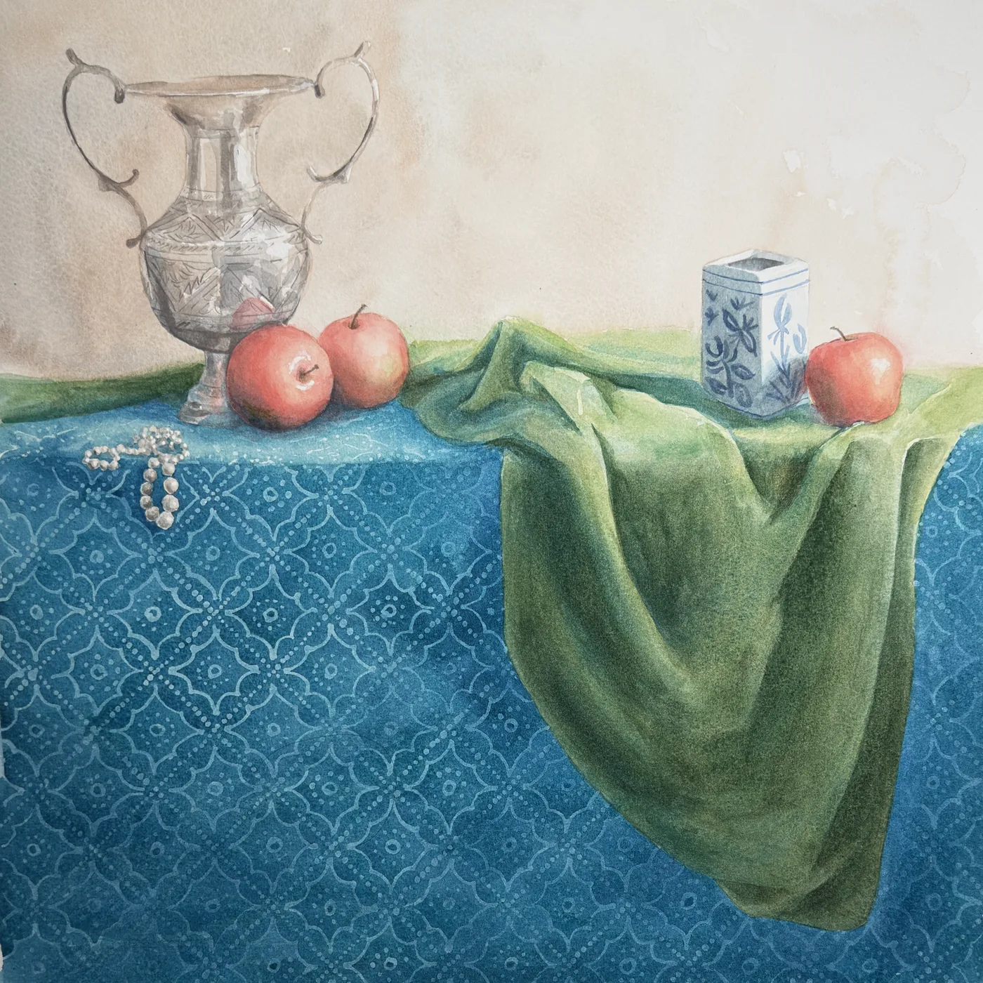 Watercolour still life of a silver urn, apples, a blue and white tea caddy and green drapery on a patterned blue cloth, by Kirsten Griffiths