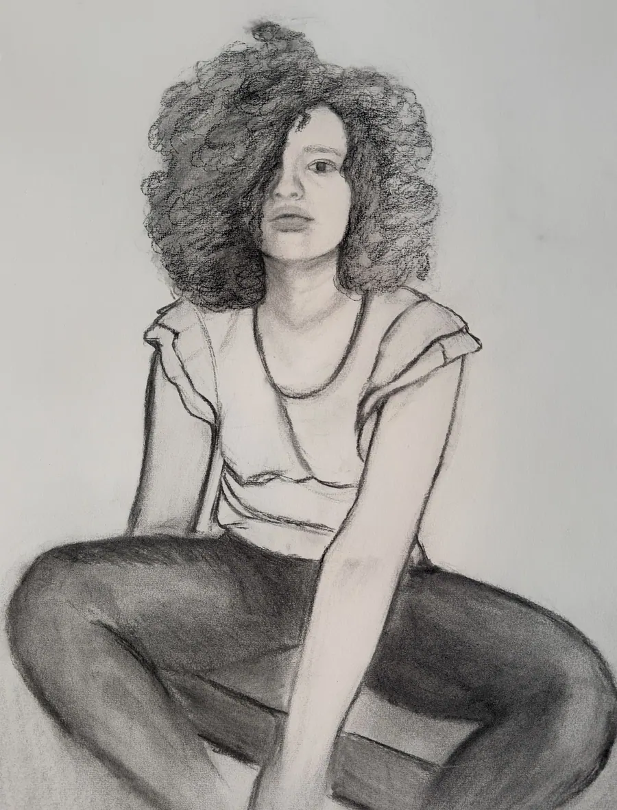 Charcoal drawing of a young woman with a full halo of curly hair sitting with her legs crossed, looking off to one side.